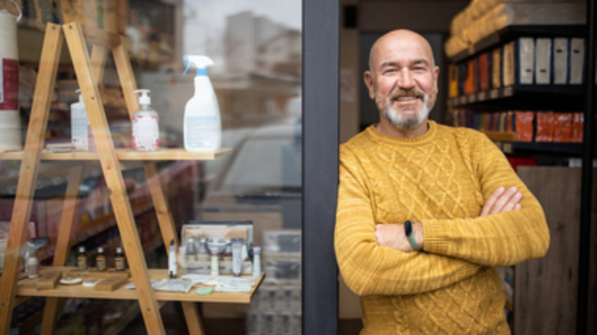 Proud owner standing with arms crossed in front of his store