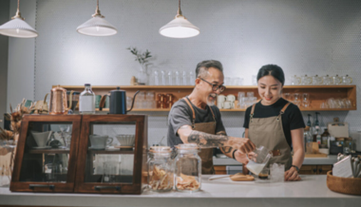 asian chinese senior male barista teaching his daughter making coffee at cafe bar counter