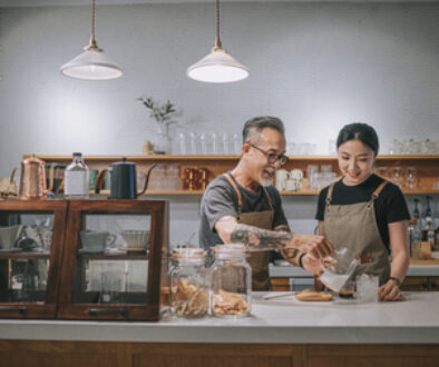 asian chinese senior male barista teaching his daughter making coffee at cafe bar counter
