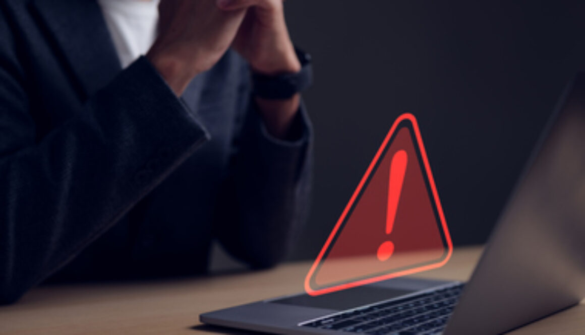 Computer notification error maintenance concept. Businessman or personnel, programmer, or developer using a computer laptop with a triangle warning exclamation red sign trouble caution.