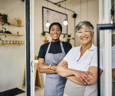 Coffee shop, senior woman manager portrait with barista feeling happy about shop success. Female server, waitress and small business owner together proud of cafe and bakery growth with a smile