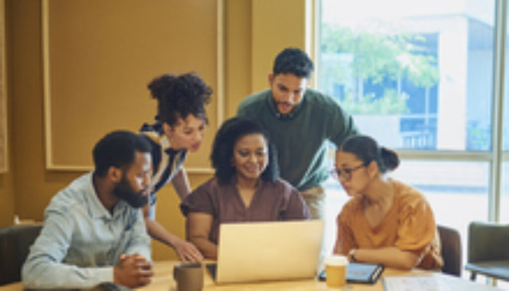 Diverse Colleagues Gathered Around Laptop In Modern Office