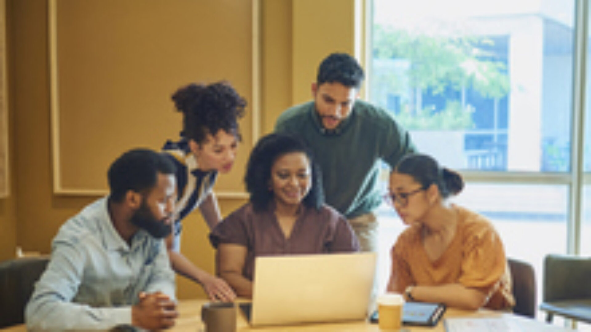 Diverse Colleagues Gathered Around Laptop In Modern Office