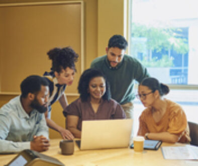 Diverse Colleagues Gathered Around Laptop In Modern Office