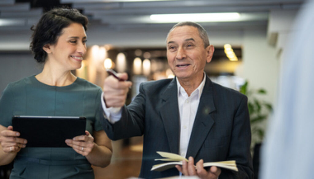Senior executive collaborating with younger employees inside business workspace.