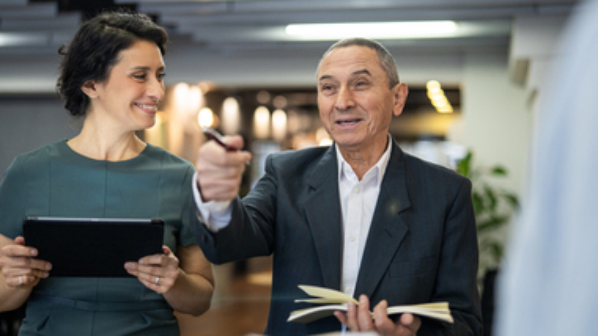 Senior executive collaborating with younger employees inside business workspace.