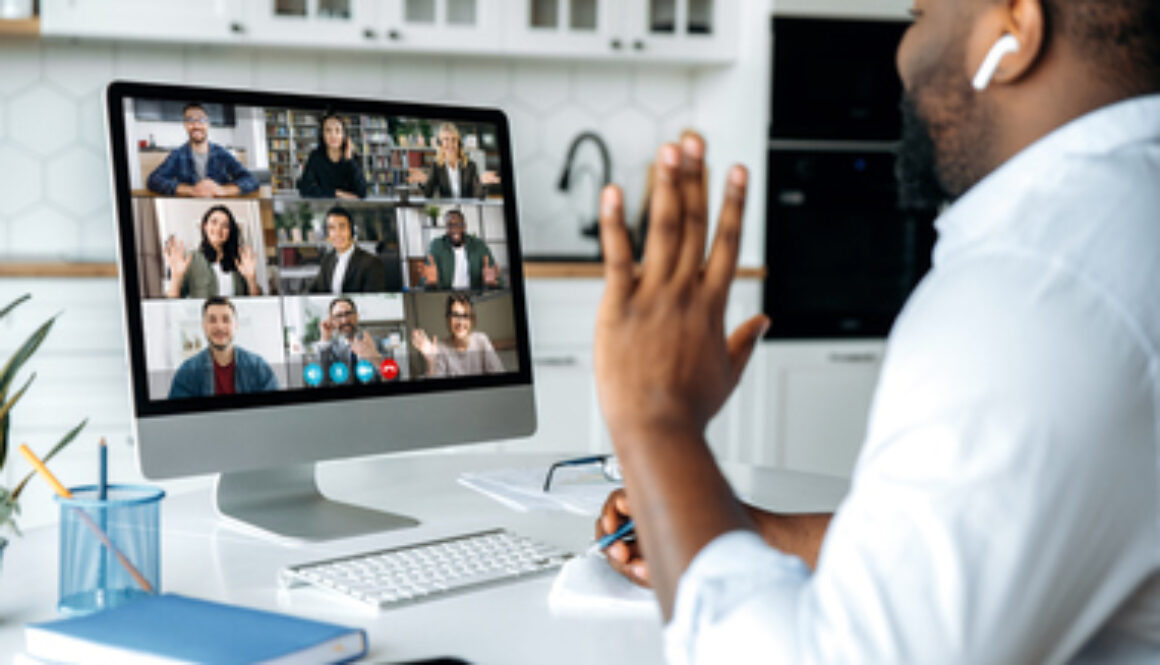 Video call, online conference. Over shoulder view of african american man at computer screen with multinational group of successful business people, virtual business meeting, work from home concept