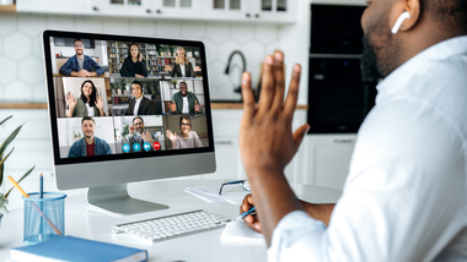 Video call, online conference. Over shoulder view of african american man at computer screen with multinational group of successful business people, virtual business meeting, work from home concept