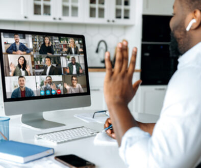 Video call, online conference. Over shoulder view of african american man at computer screen with multinational group of successful business people, virtual business meeting, work from home concept
