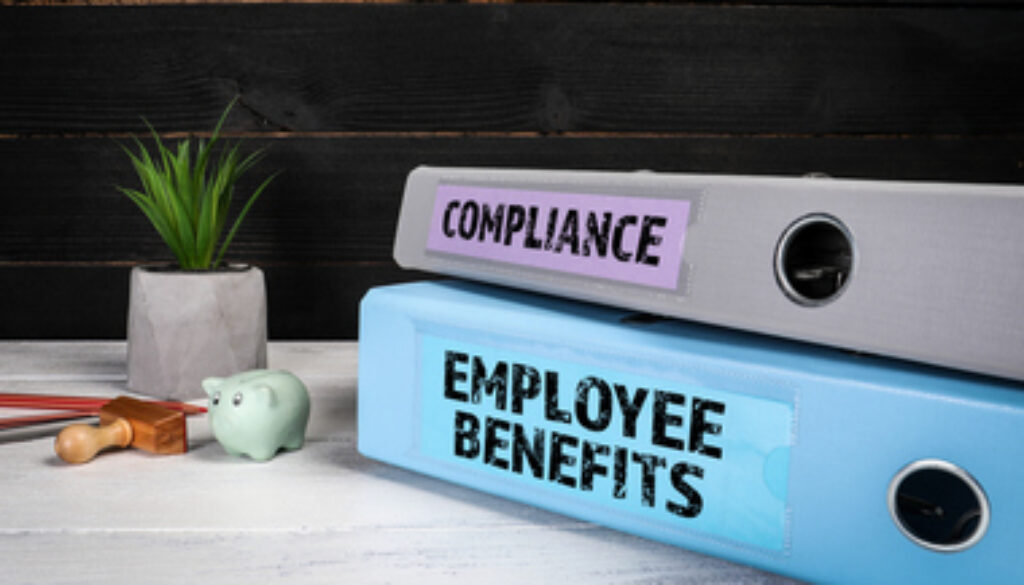 EMPLOYEE BENEFITS and COMPLIANCE. Document binders, folders on a wooden office desk