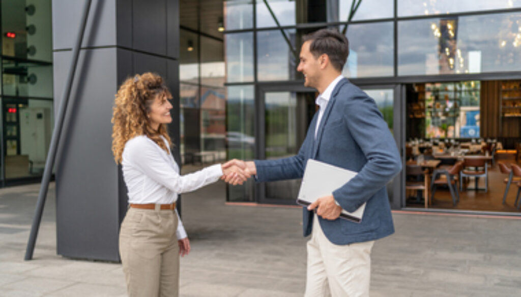 Businesspeople shaking hands outside office building