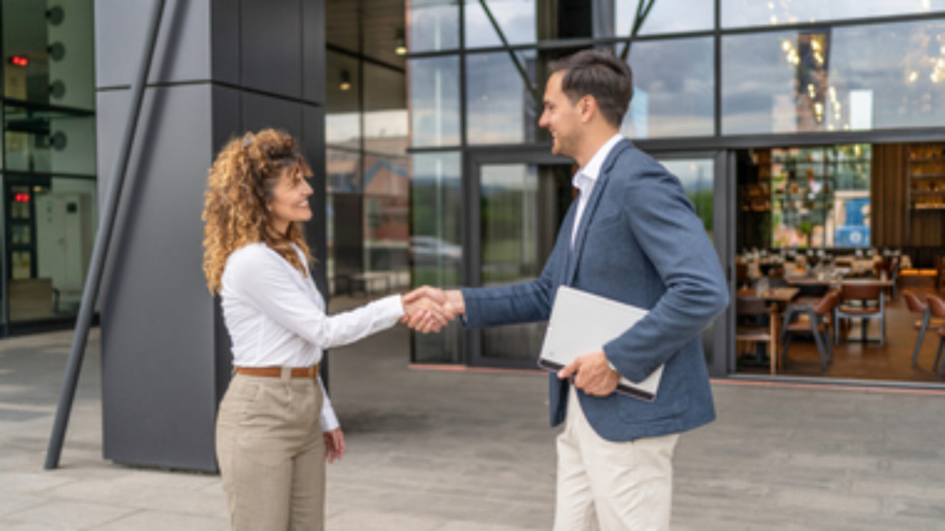 Businesspeople shaking hands outside office building