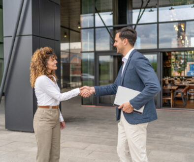 Businesspeople shaking hands outside office building
