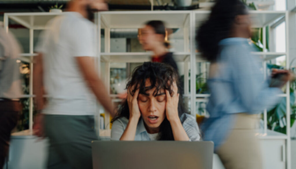 Stressed businesswoman holding head in busy office
