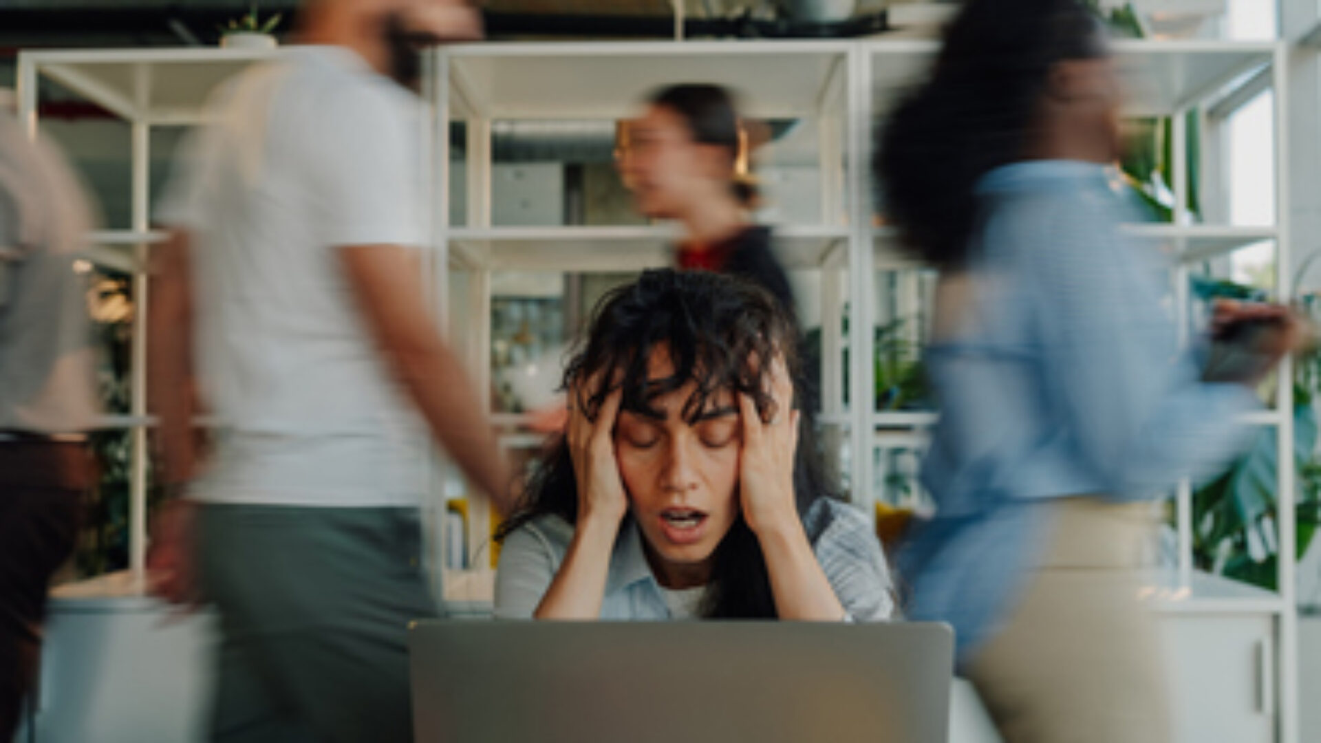 Stressed businesswoman holding head in busy office