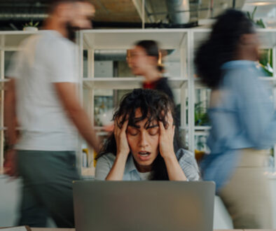 Stressed businesswoman holding head in busy office