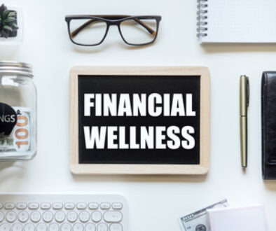 Financial Wellness. Black frame with word Financial Wellness on table with mason jar saving bank, stationery and glasses. Investment in life insurance and healthcare concept