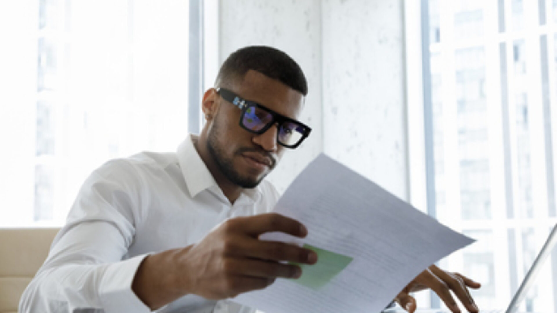 Serious African American manager in stylish glasses reading corporate document