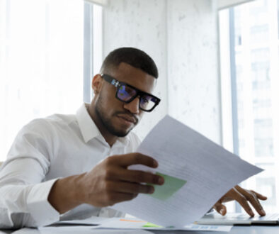 Serious African American manager in stylish glasses reading corporate document